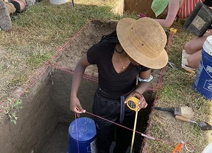 Field Archaeology student measuring excavation site at Hartwick College's Pine Lake Environmental Campus dig